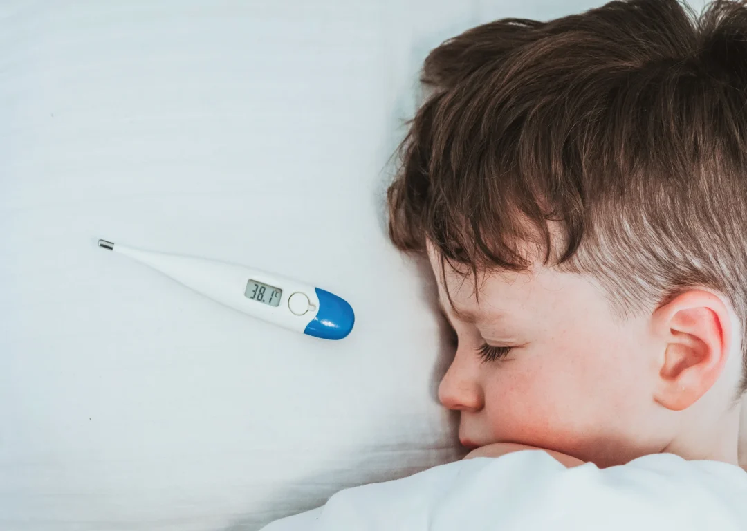 Young boy in bed with a fever.