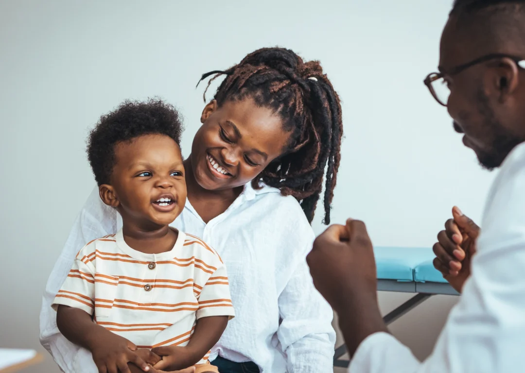Young boy sat on mother's lap in doctor's office.