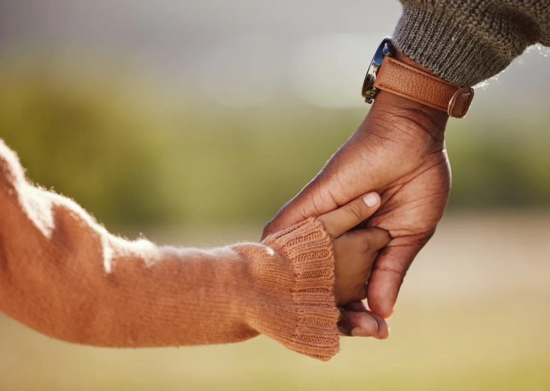 Man wearing watch holding hand of young daughter.
