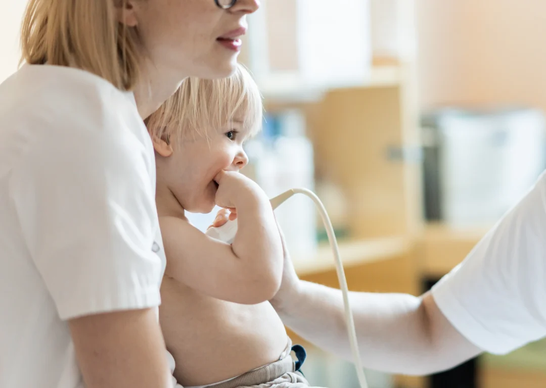 Blonde little boy sits on mother's knee while having an Echocardiogram.