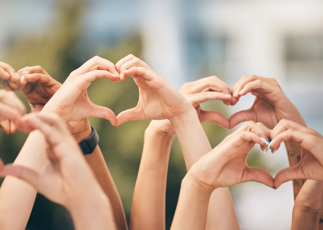 Multiple teenagers holding up their hands in a heart shape.